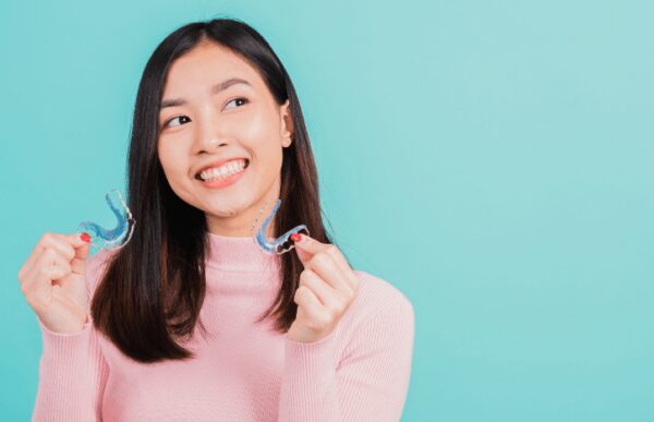 lady holding retainers with questions about post orthodontic care
